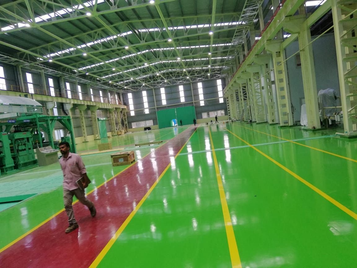 Green and red epoxy floor with safety lanes in a factory hall
